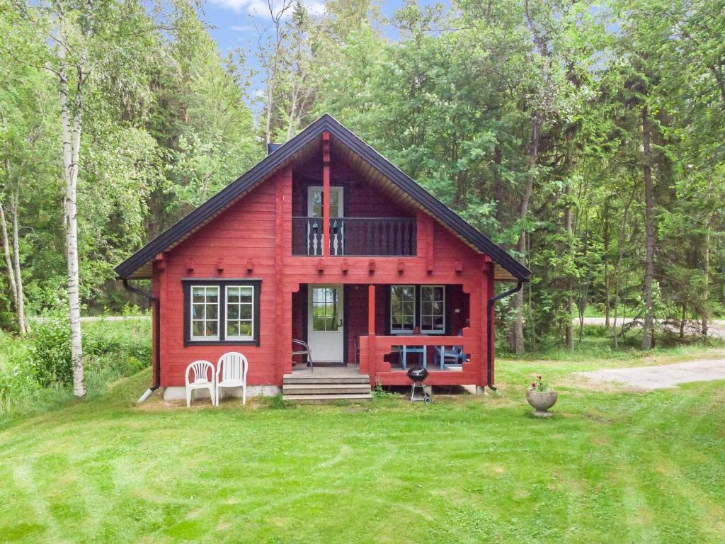 una casa rossa con due sedie bianche in un cortile di Holiday Home Strandkulla 7 by Interhome a Närpiö