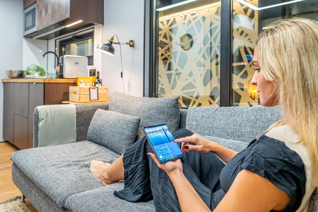 a woman sitting on a couch looking at her cell phone at The Homeboat Company Albufeira in Albufeira