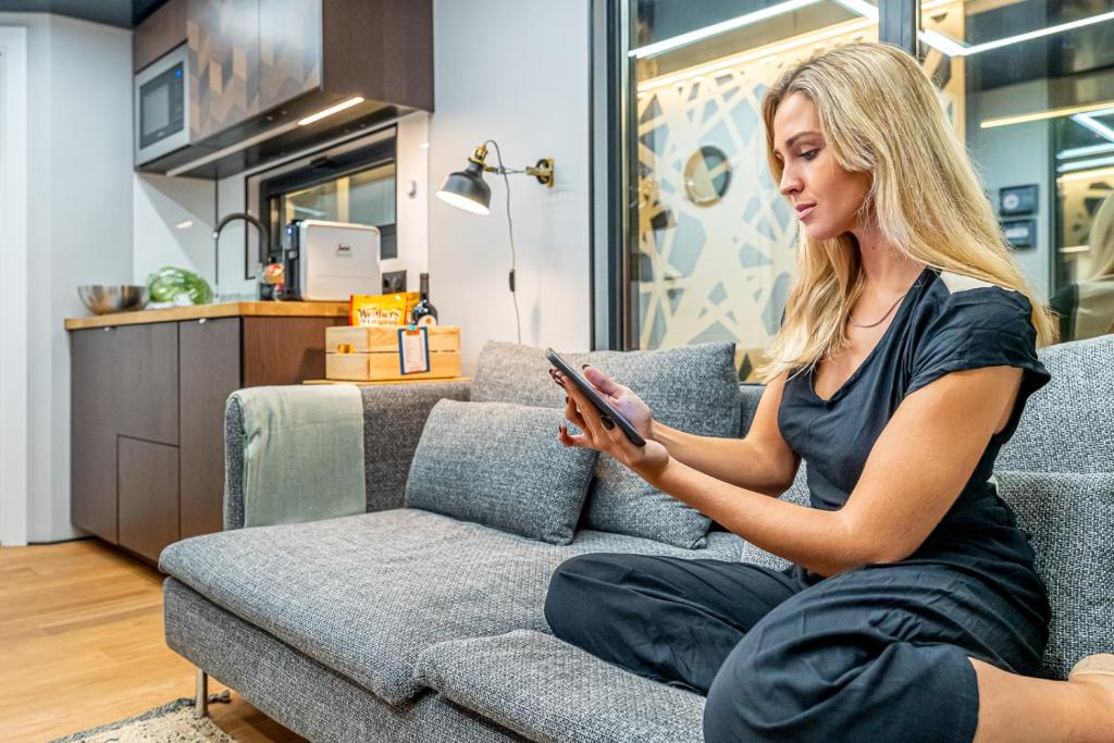 a woman sitting on a couch looking at her cell phone at The Homeboat Company Albufeira in Albufeira