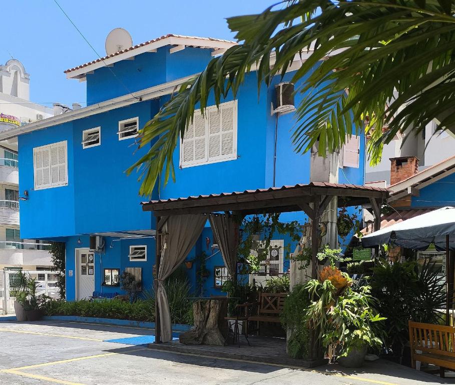un edificio blu con un albero di fronte di Pousadinha e Residencial Sto António - Praia de Bombas/Bombinhas-SC a Bombinhas