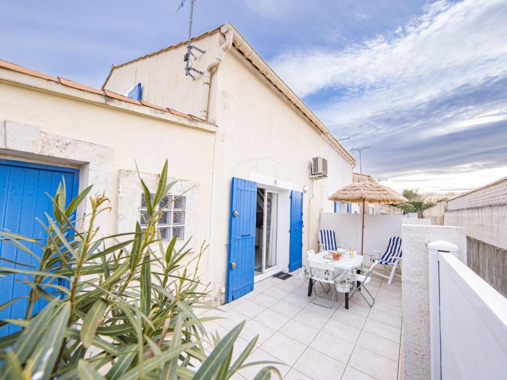 une maison blanche avec des portes bleues, une table et des chaises dans l'établissement Holiday Home La Plagette by Interhome, à Aigues-Mortes