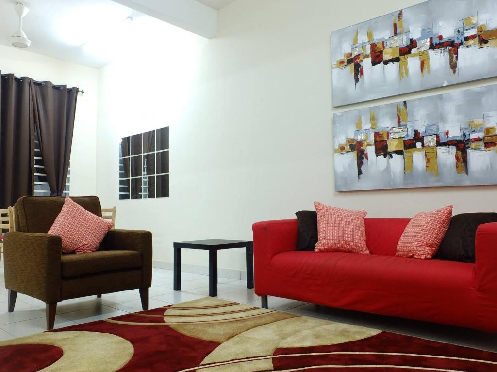 sala de estar con sofá rojo y 2 sillas en Dillenia Nilai Homestay en Nilai