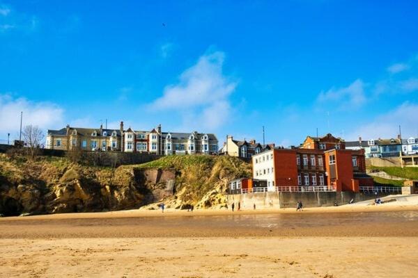 a beach with houses on top of a hill at Boho Bay Two - Seaside Escape in Cullercoats