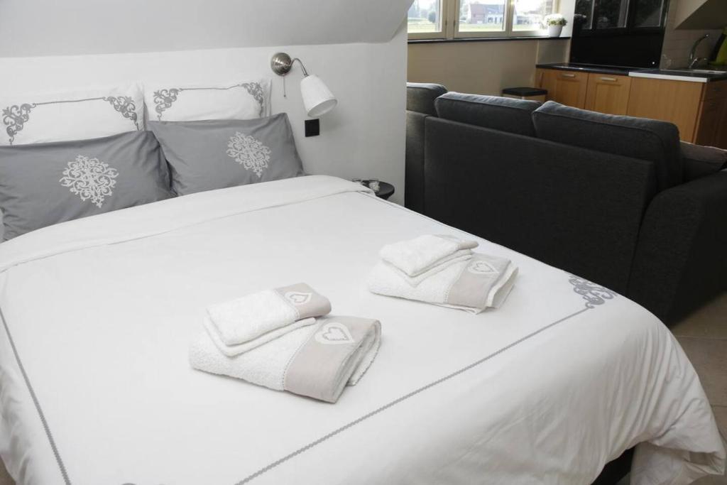 a large white bed with two white towels on it at Au Jardin du Trieu in Pecq