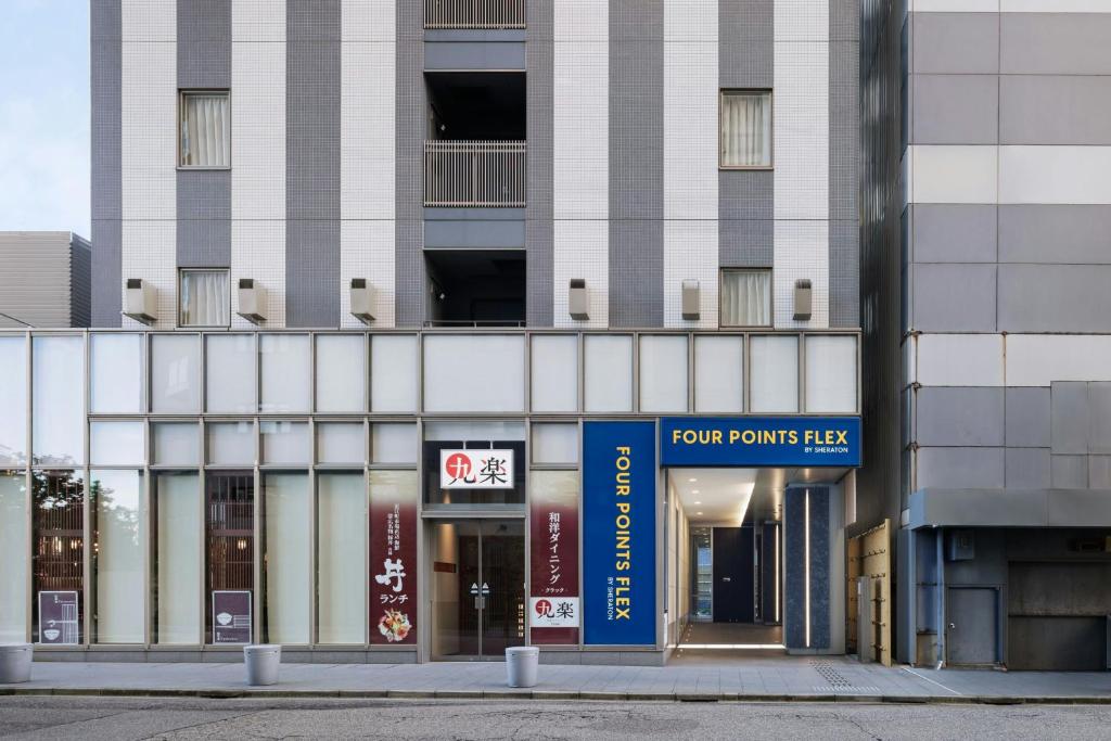 金沢市にあるフォーポイント フレックス by シェラトン 金沢の正面に看板がある背の高い白い建物