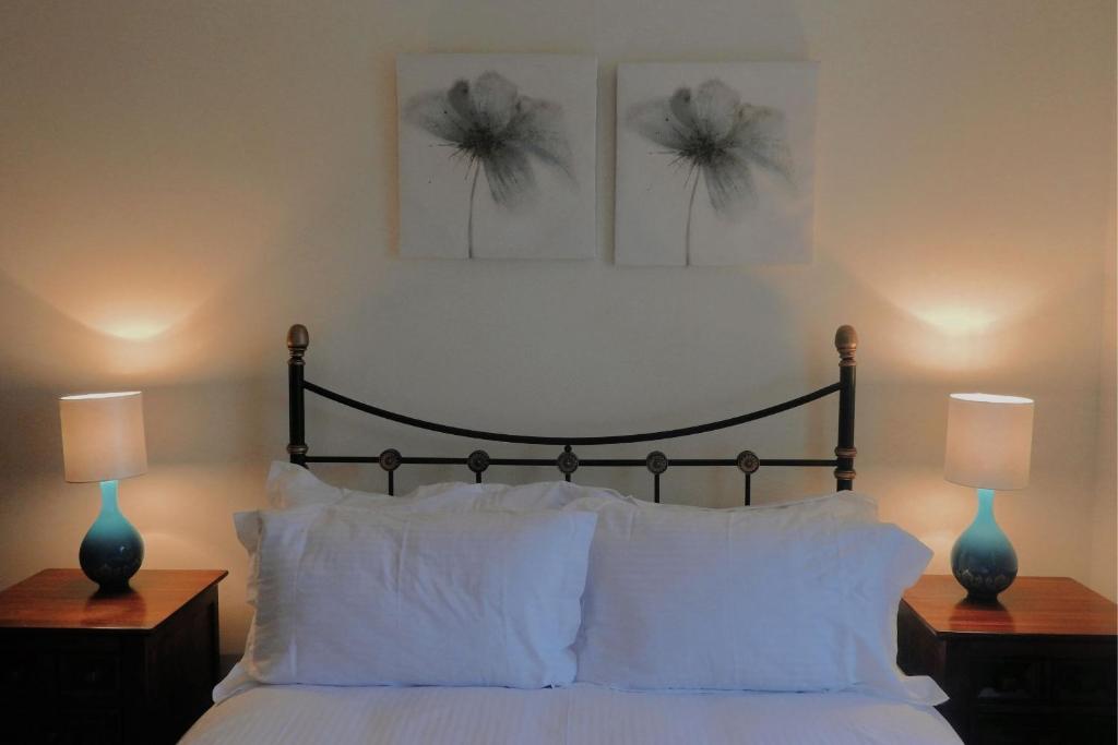 a bedroom with a bed with white pillows and two lamps at Harebell Cottage in Killean