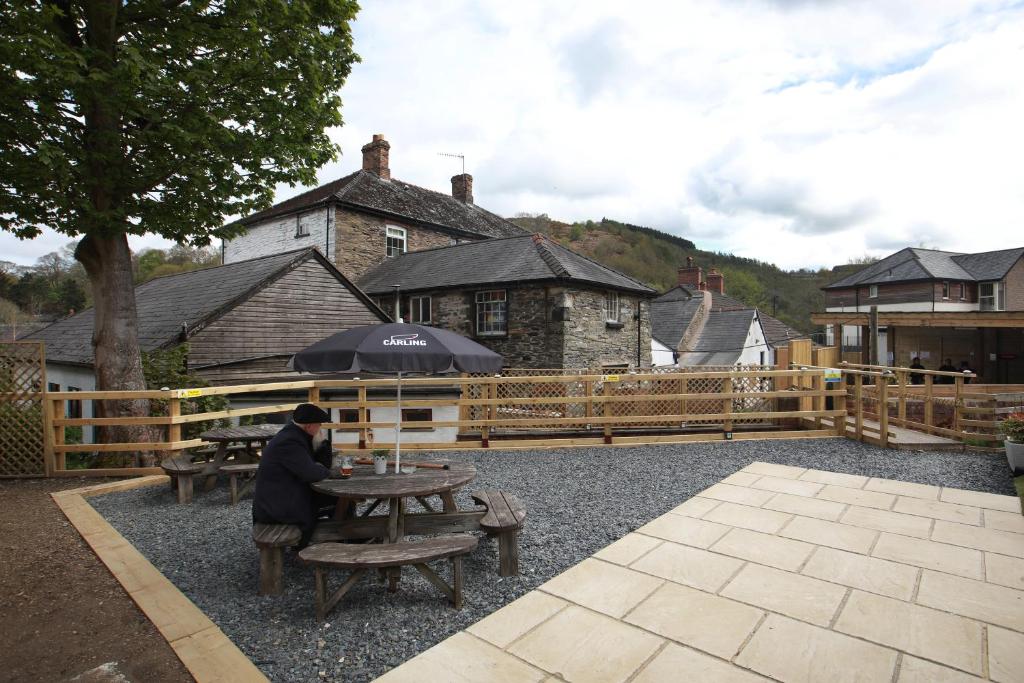 a person sitting at a picnic table with an umbrella at OYO Glyn Valley Hotel in Llansantffraid Glyn Ceiriog