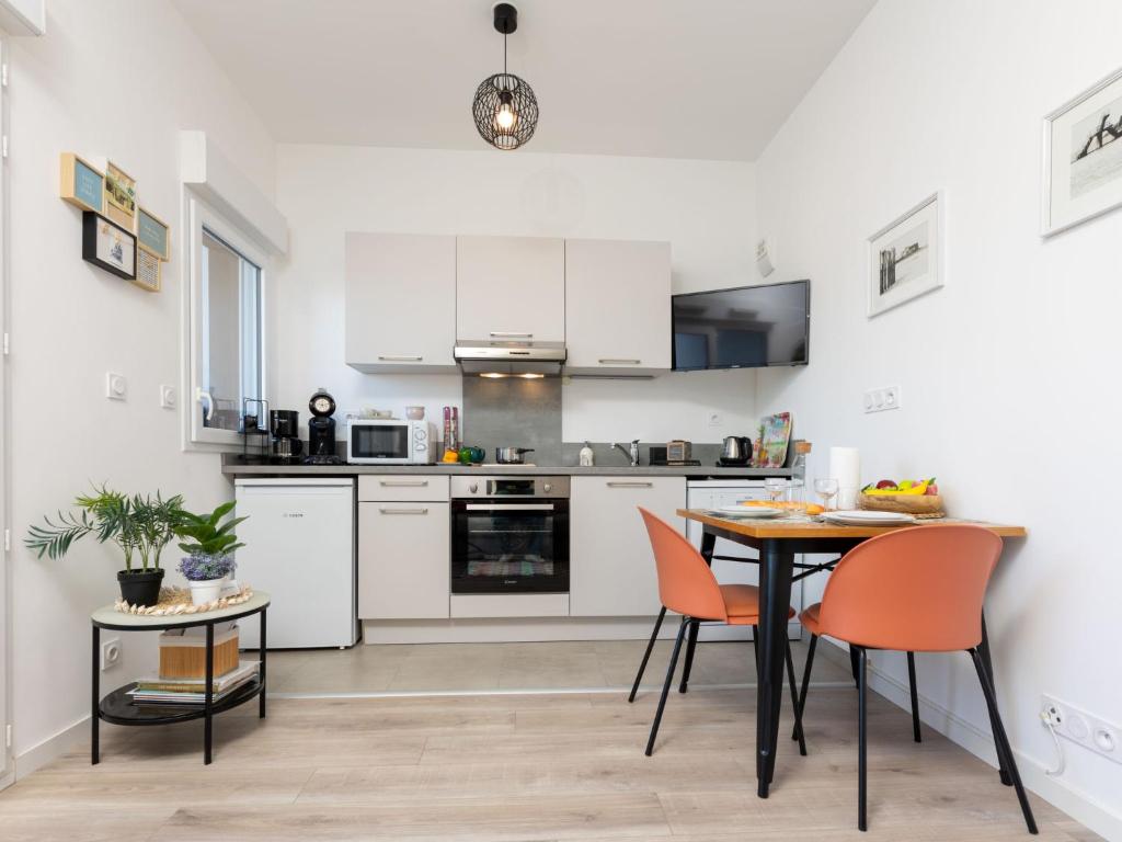 une cuisine avec des armoires blanches et une table et des chaises dans l'établissement Studio Résidence de l'Hermine by Interhome, à Saint-Malo
