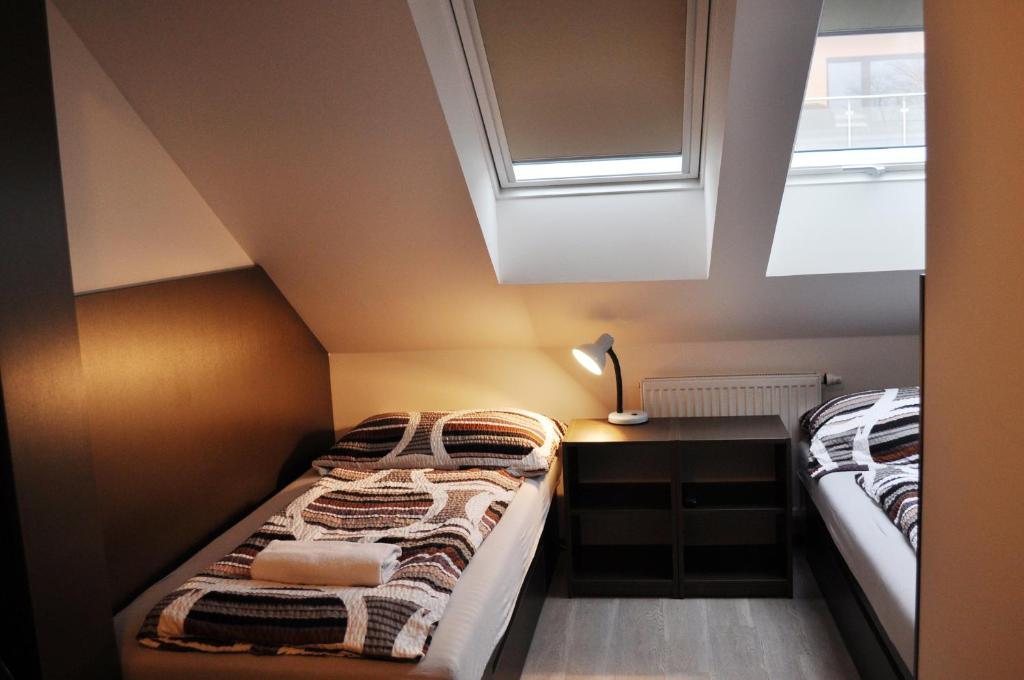 two beds in a small room with a window at Penzion Modrá růže in Uherské Hradiště