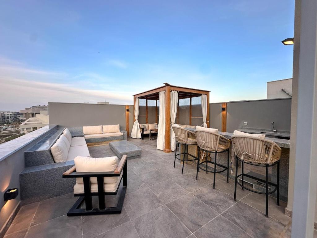 a rooftop patio with a couch and tables and chairs at velora Studio roof in sodic villette compound in New cairo