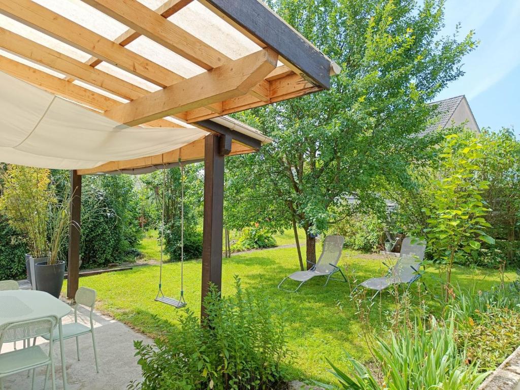 a patio with a table and chairs under a wooden roof at Gite au Petit Verger in Masevaux
