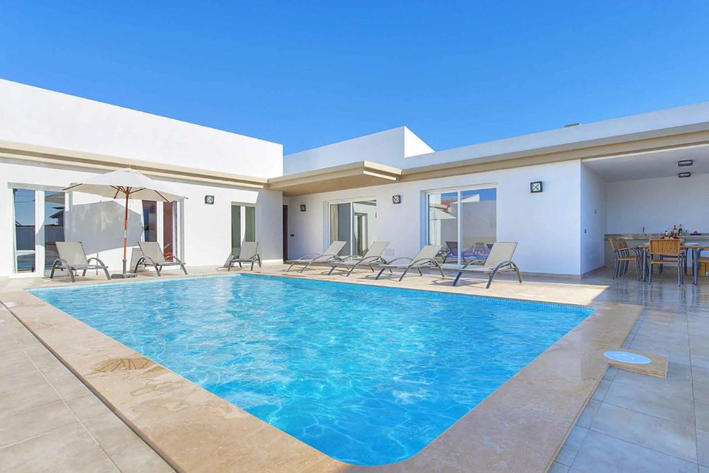 Villa Betty في كالا إن بلانيس: مسبح في بيت فيه كراسي وطاولة