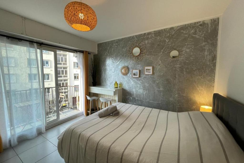 une chambre avec un grand lit et une grande fenêtre dans l'établissement La plage d'Augustin, au Havre