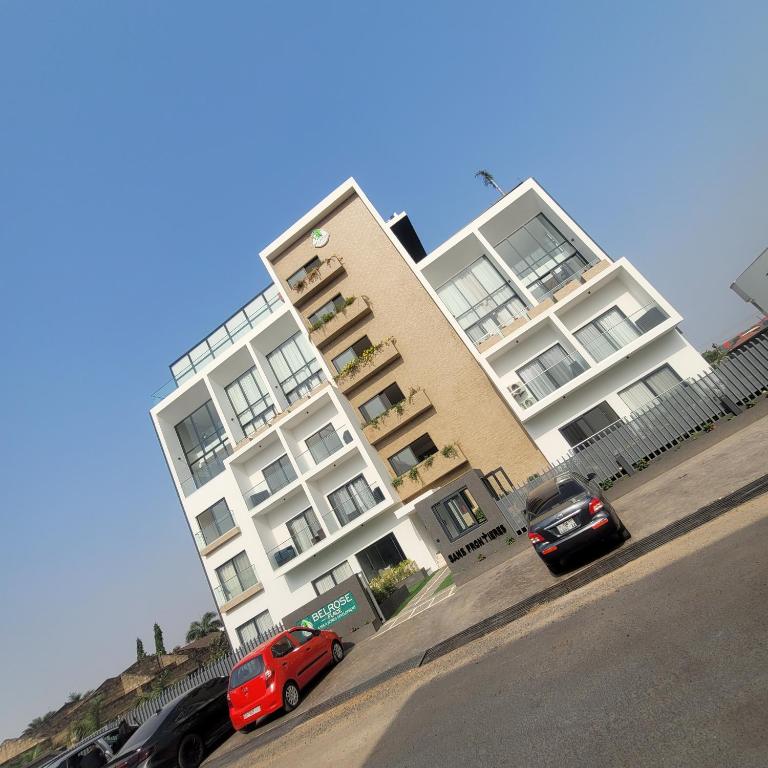 une voiture rouge garée devant un bâtiment dans l'établissement RT LUXURY ONE BEDROOM DUPLEX At BELROSE PLACE, à Accra
