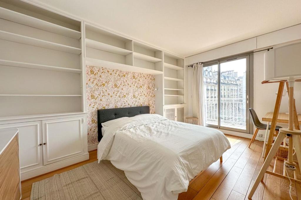 a bedroom with a bed and a window and shelves at Flexliving - room - Ternes in Paris