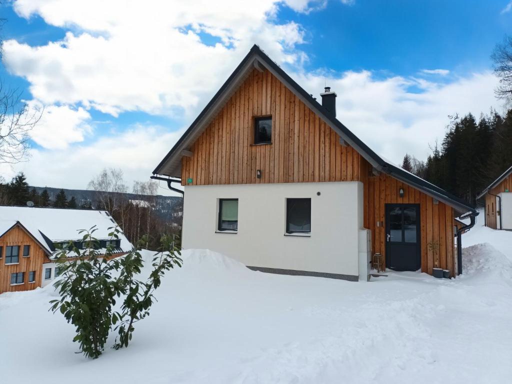 a wooden house in the snow with snow at Holiday Home Muhu by Interhome in Smržovka