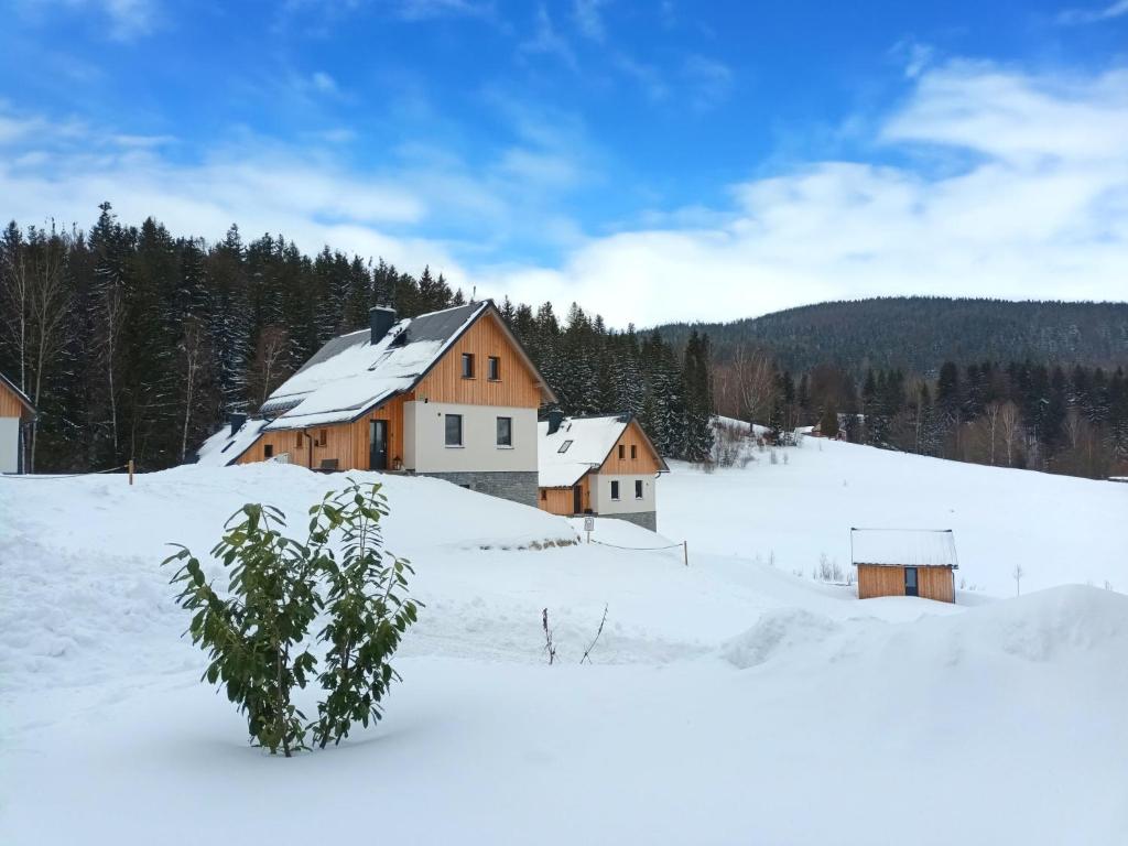 a group of buildings in a snow covered field at Apartment Chalupa 13ka - Dolní apartmán by Interhome in Smržovka