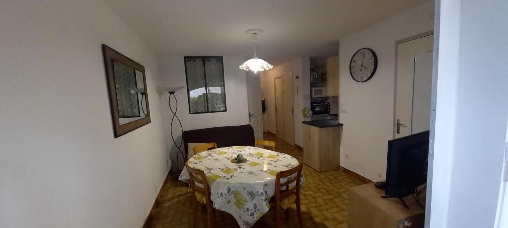 - un salon avec une table et une horloge murale dans l'établissement Résidence BORA BORA, à Marseillan