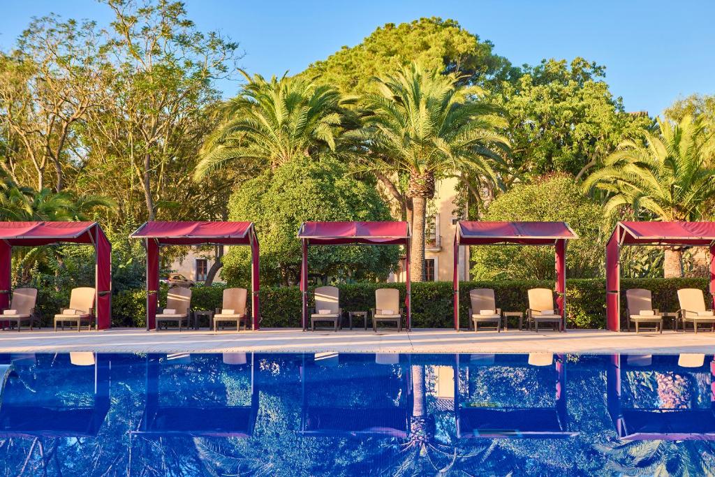a pool at a resort with chairs and trees at Son Julia Country House & Spa in Llucmajor