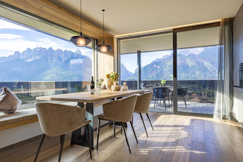 a dining room with a table and chairs and a large window at Luxury Dolomites Apartments in Dobbiaco