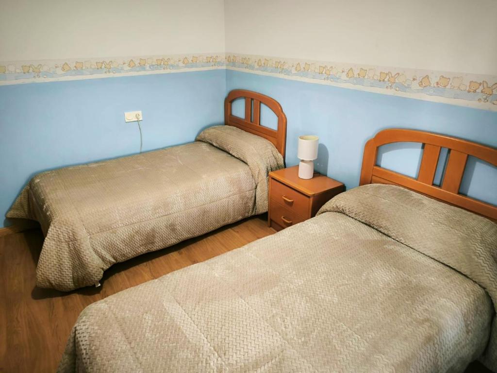 dwa łóżka w pokoju z niebieskimi ścianami i drewnianą podłogą w obiekcie Apartamento Padial w mieście Nerja