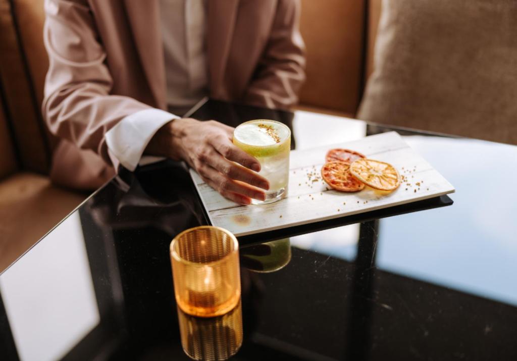 a man holding a drink on a table with a plate of food at Valtur Cervinia Cristallo Ski Resort in Breuil-Cervinia