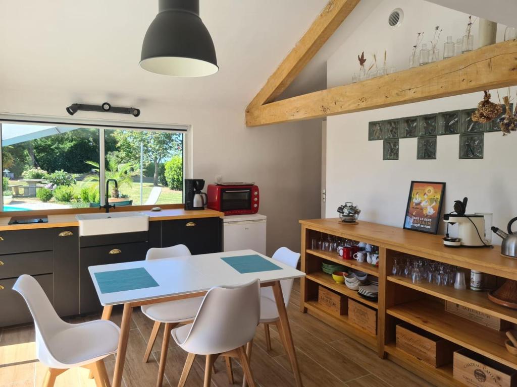 a kitchen with a table and white chairs at LOFT de BARTUEL à 5 min de NOGARO in Arblade-le-Haut