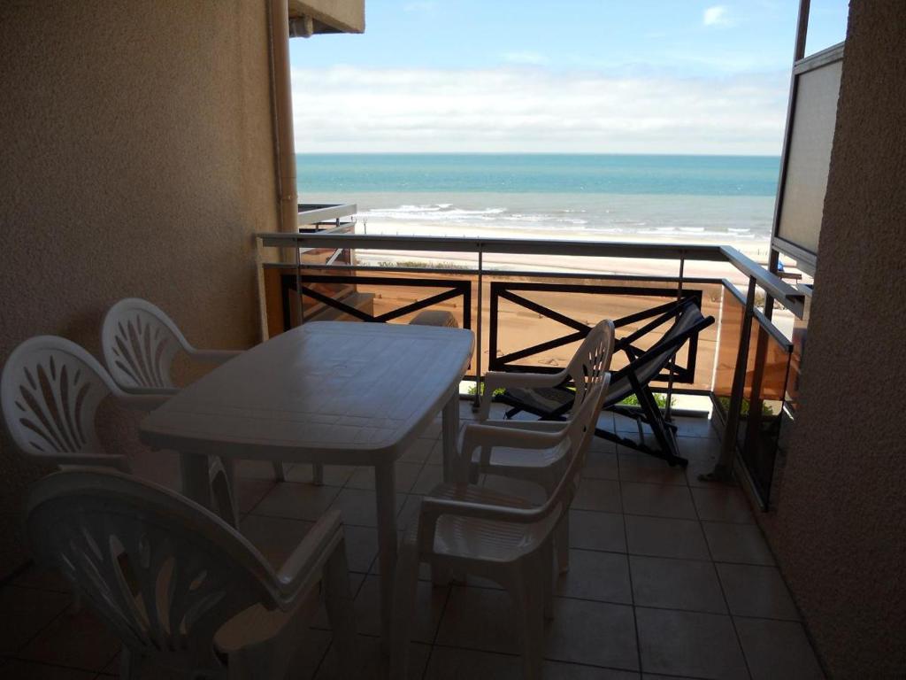 une table et des chaises sur un balcon avec vue sur l'océan dans l'établissement appartement en frond de mer, à Soulac-sur-Mer