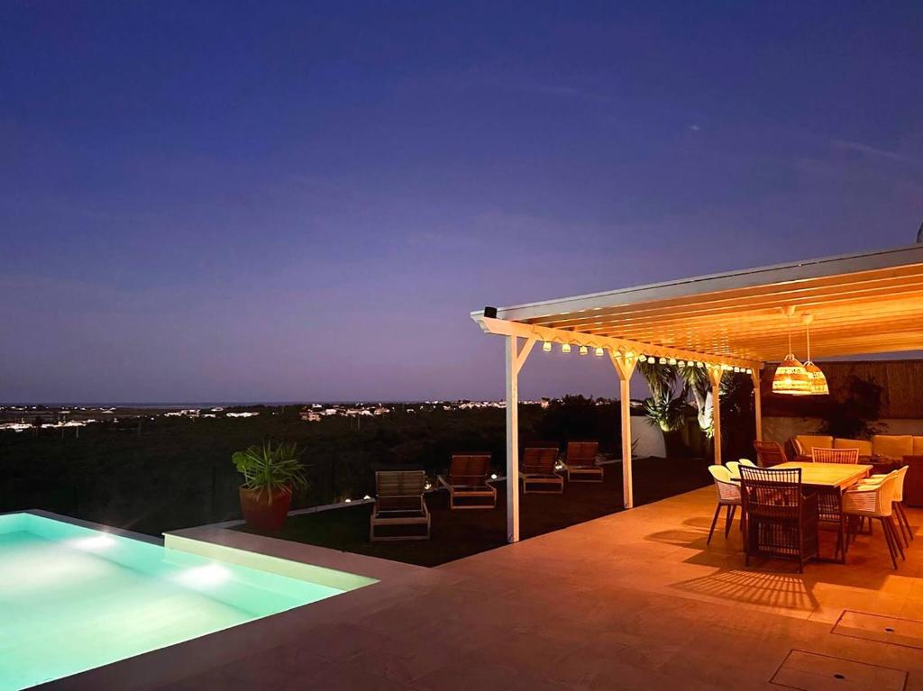 a patio with a table and a pool at night at Casa Belavista - Fuzeta by Junto ao Mar in Moncarapacho