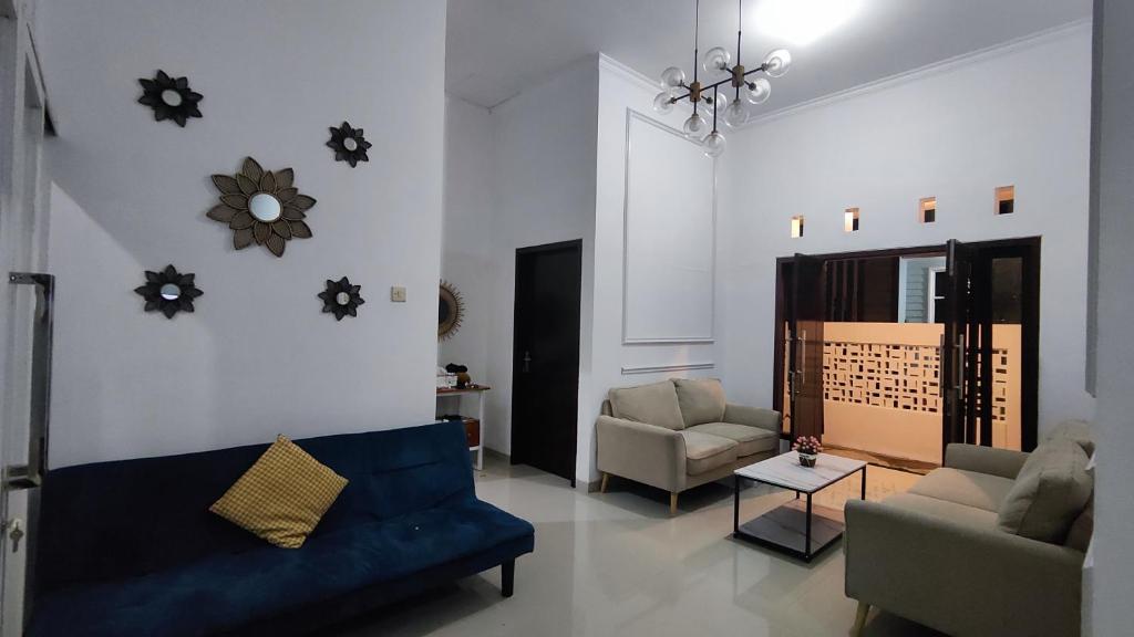 a living room with a blue couch and two chairs at Flamboyan8 syariah Homestay in Dadapan