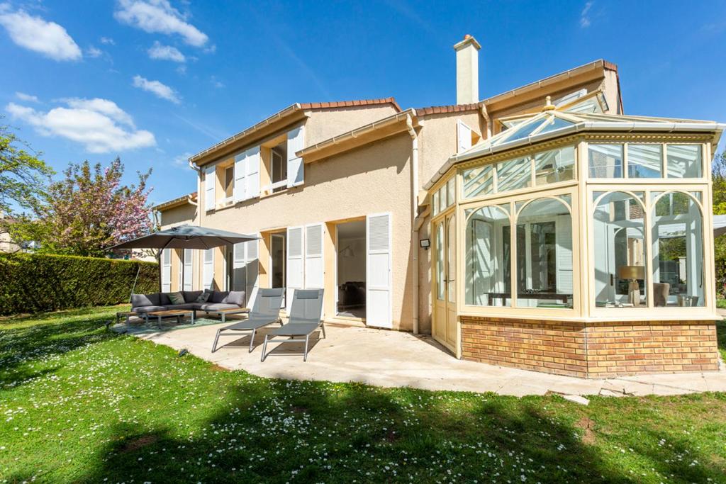une maison avec une véranda et des chaises sur une terrasse dans l'établissement Maison au calme près de Versailles, à Louveciennes