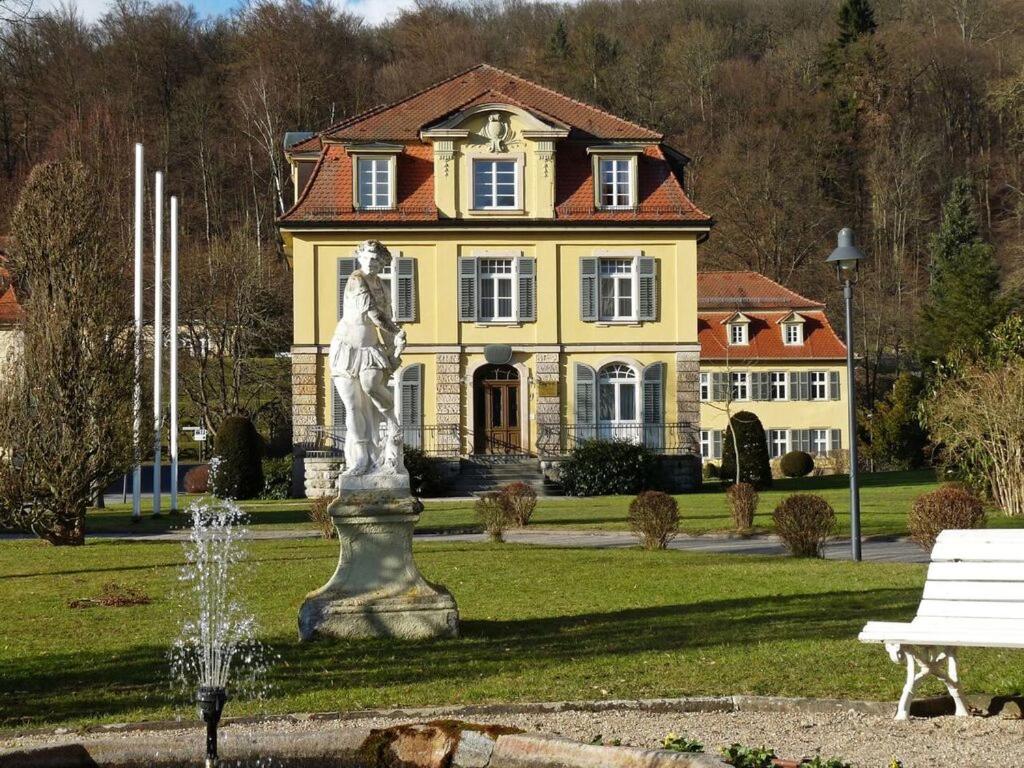 a statue in front of a yellow house with a fountain at Philosophenvilla in Staatsbad Brückenau