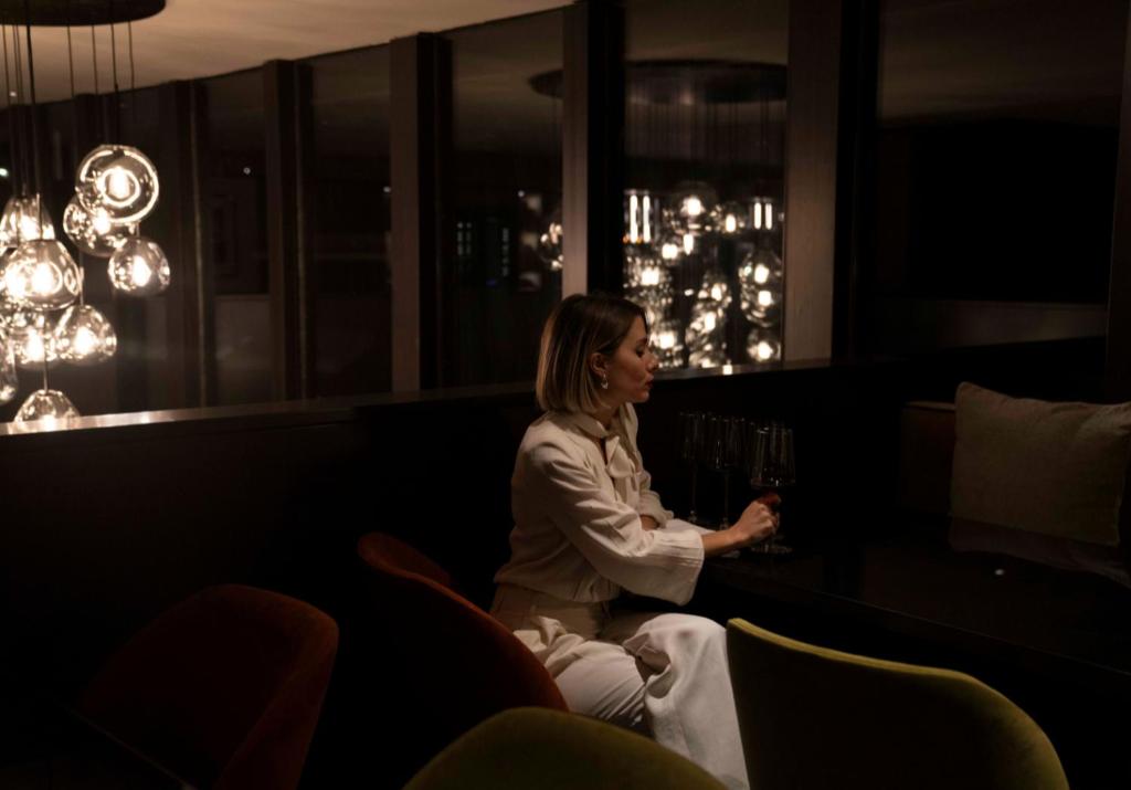 a woman sitting at a bar with a glass of wine at Valtur Cervinia Cristallo Ski Resort in Breuil-Cervinia