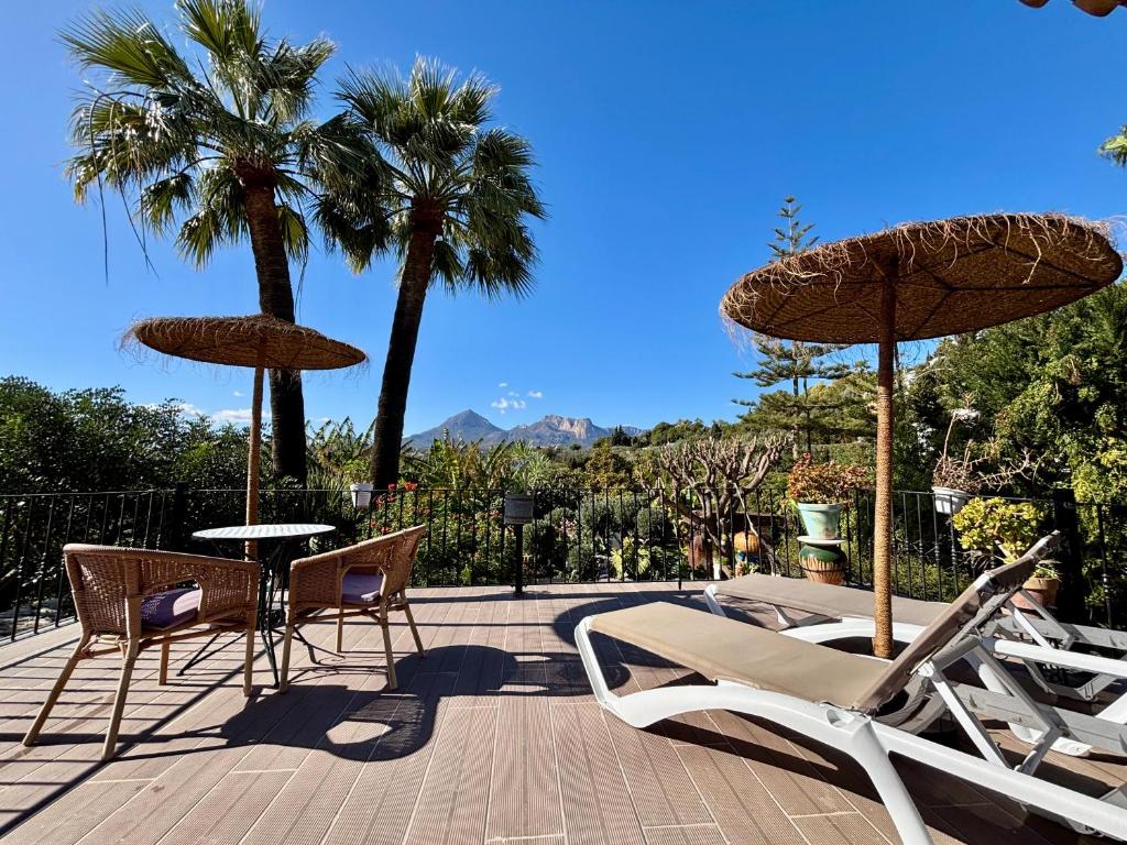 a patio with chairs and umbrellas and palm trees at Hotel Altea Paradise 1917 - Adults Only in Altea