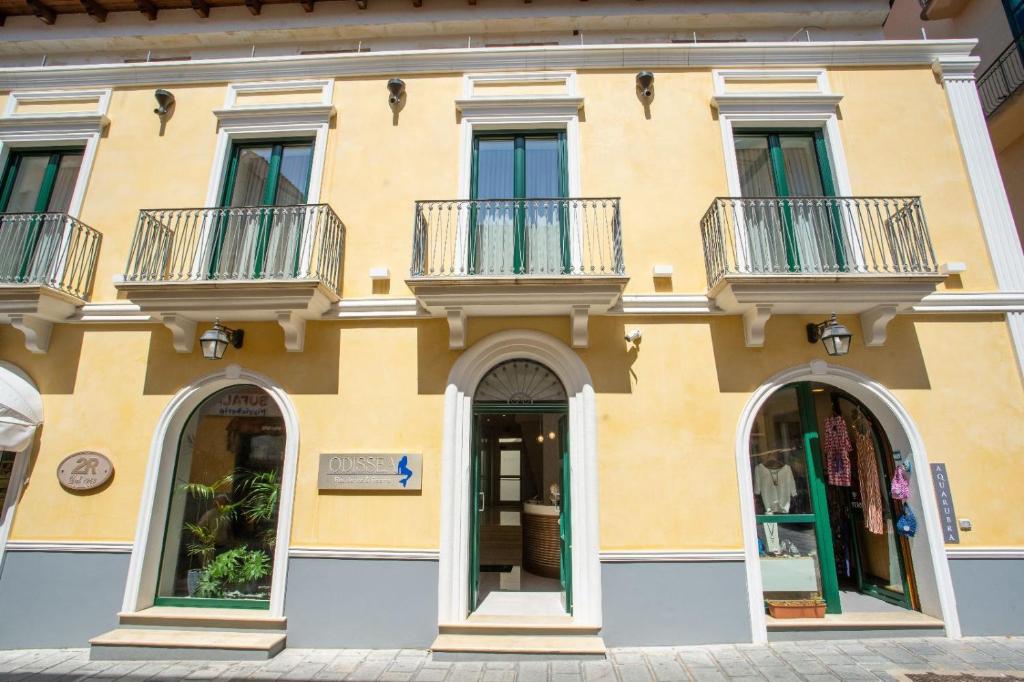 a yellow building with two balconies on it at Odissea Residence e Rooms in Santa Maria di Castellabate