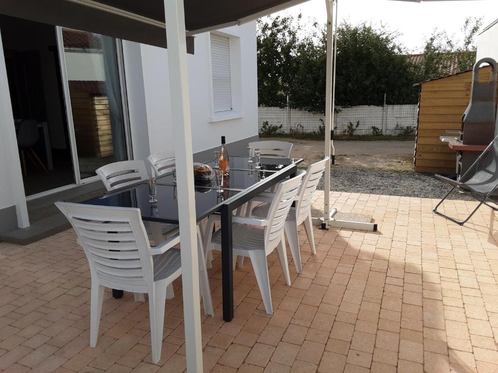 un tavolo e sedie su un patio con ombrellone di Maison du pêcheur, forêt et océan a Notre-Dame-de-Monts