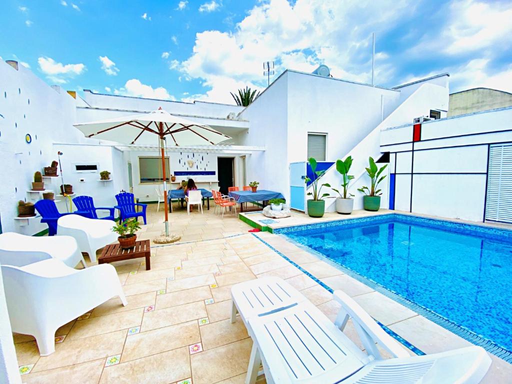 una piscina con muebles blancos y una casa blanca en Casa Mondrian - Comfort e Design con Piscina Privata, en Tiggiano