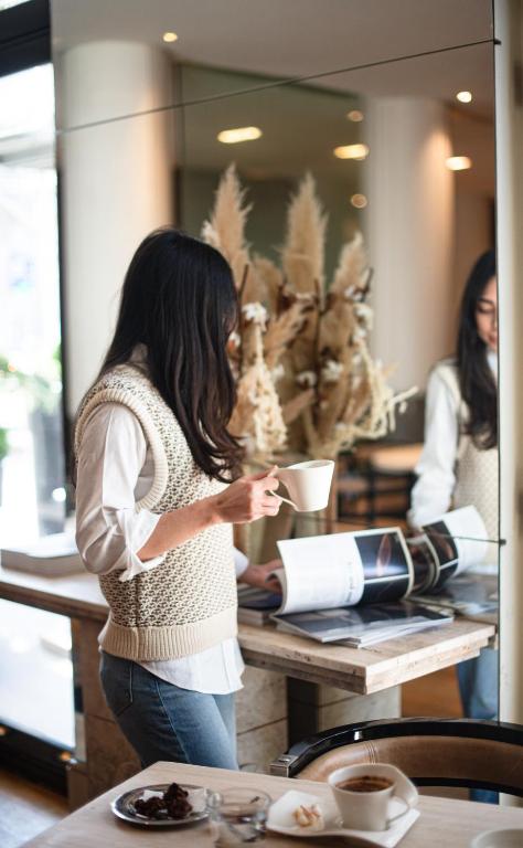 a woman standing at a table with a cup of coffee at Grand Hôtel Champs-Elysées in Paris
