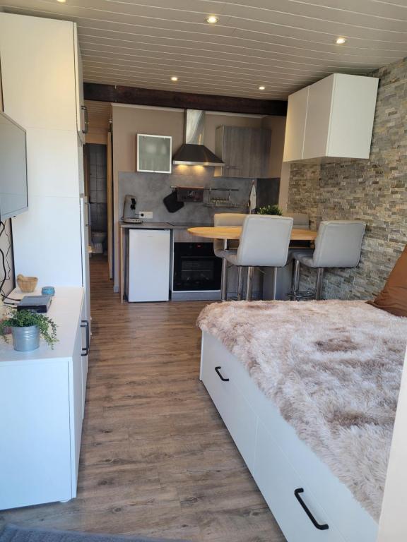 a kitchen with white cabinets and a wooden floor at Studio cabine face au Cambre d'aze in Saint-Pierre-dels-Forcats