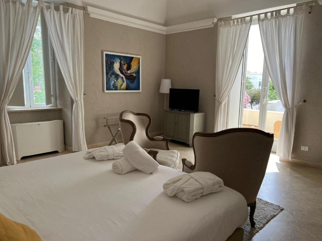 a bedroom with a large white bed with two chairs at Relais Corte Degli Aragonesi in Ischia