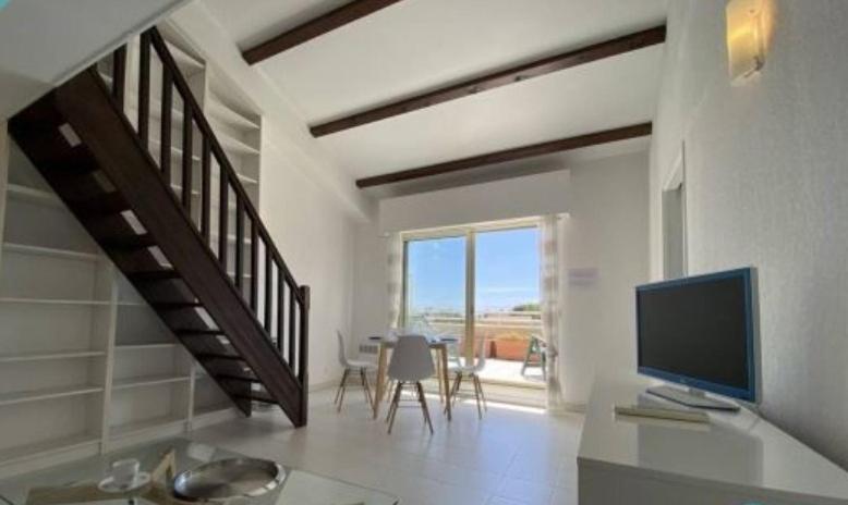 - un salon avec un bureau, une télévision et un escalier dans l'établissement Loft lumineux et calme - terrasse - piscine, à Antibes