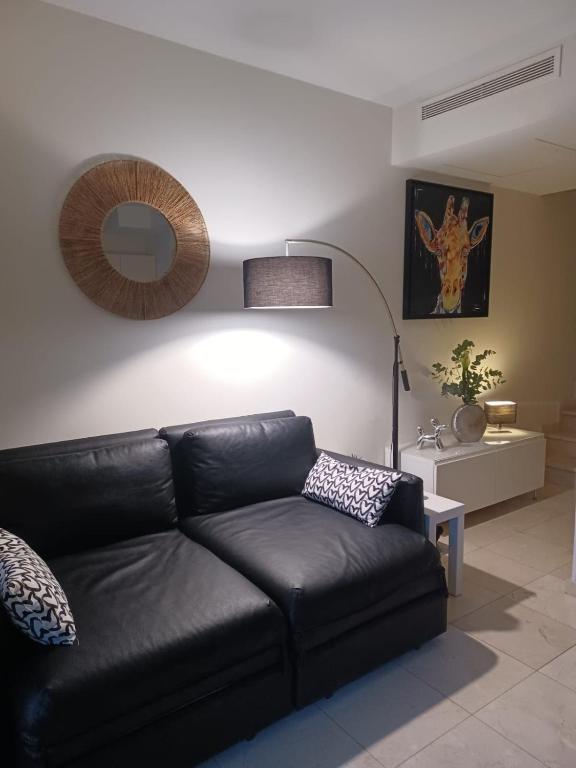 - un canapé en cuir noir dans un salon avec une lampe dans l'établissement 2 pièces en bord de mer avec piscine et jardin, à Théoule-sur-Mer