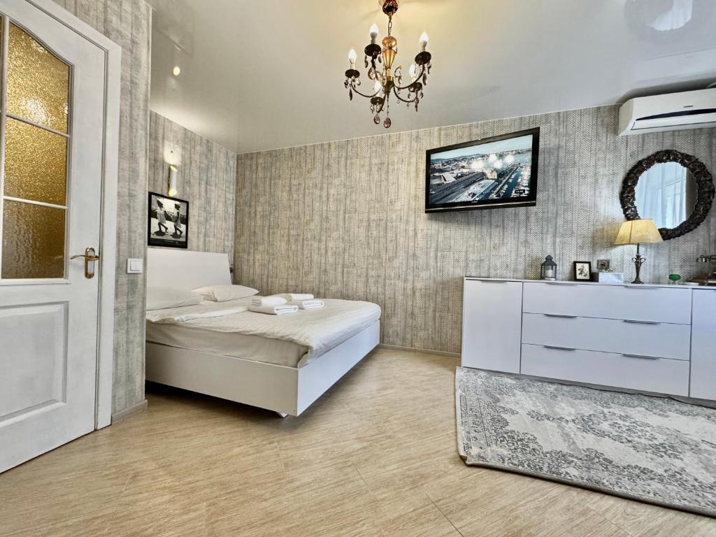 a bedroom with a bed and a mirror and a chandelier at ApartPoltava Смак Італії у самому центрі Полтави , білосніжна студія в новобудові, банківський чек in Poltava