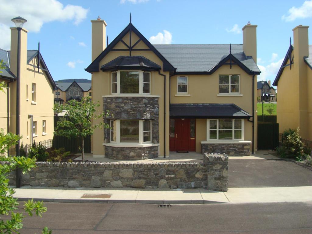 a large yellow house with a stone wall at Ardmullen 4 Bed Detached Holiday Home - Walnut in Kenmare