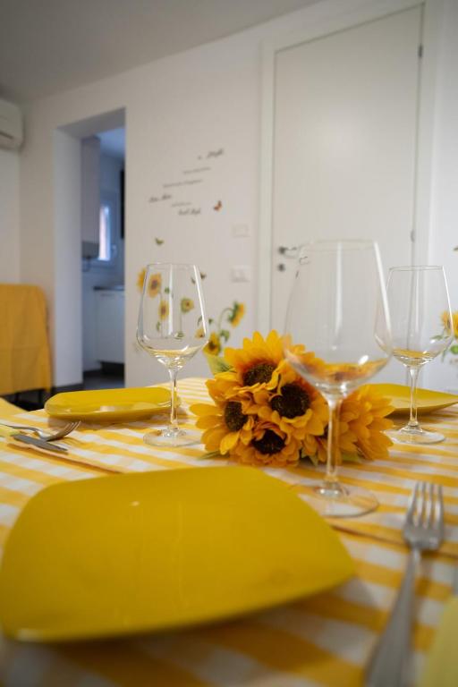a table with yellow plates and wine glasses and sunflowers at Girasole in Chioggia