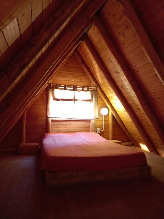 Schlafzimmer im Dachgeschoss mit einem Bett und einem Fenster in der Unterkunft Cabaña Alpina in Rodeo
