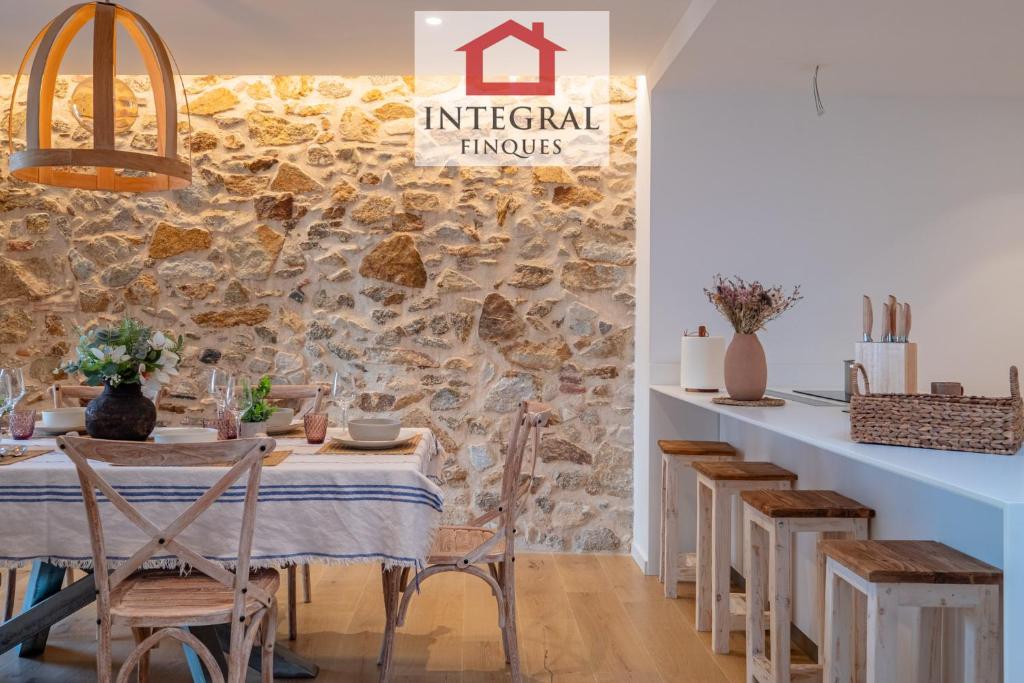 a dining room with a table and a stone wall at Apartament Bella Terra in Palamós