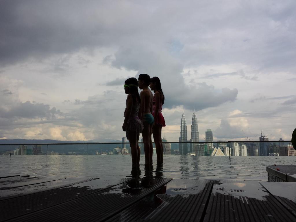 two women and a man standing next to a body of water at Amazing KLCC View @ Regalia Residence in Kuala Lumpur