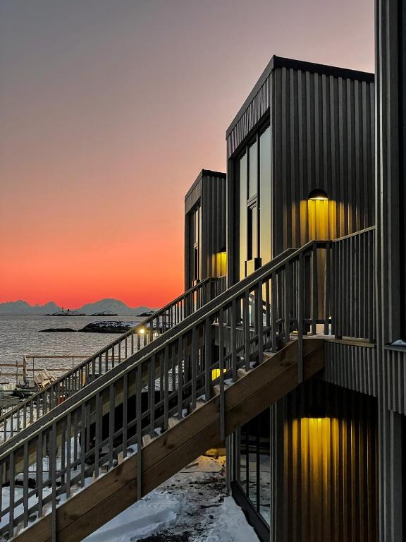a building on the beach with the sunset in the background at Modern One-Bedroom Apartment in Henningsvær in Henningsvær