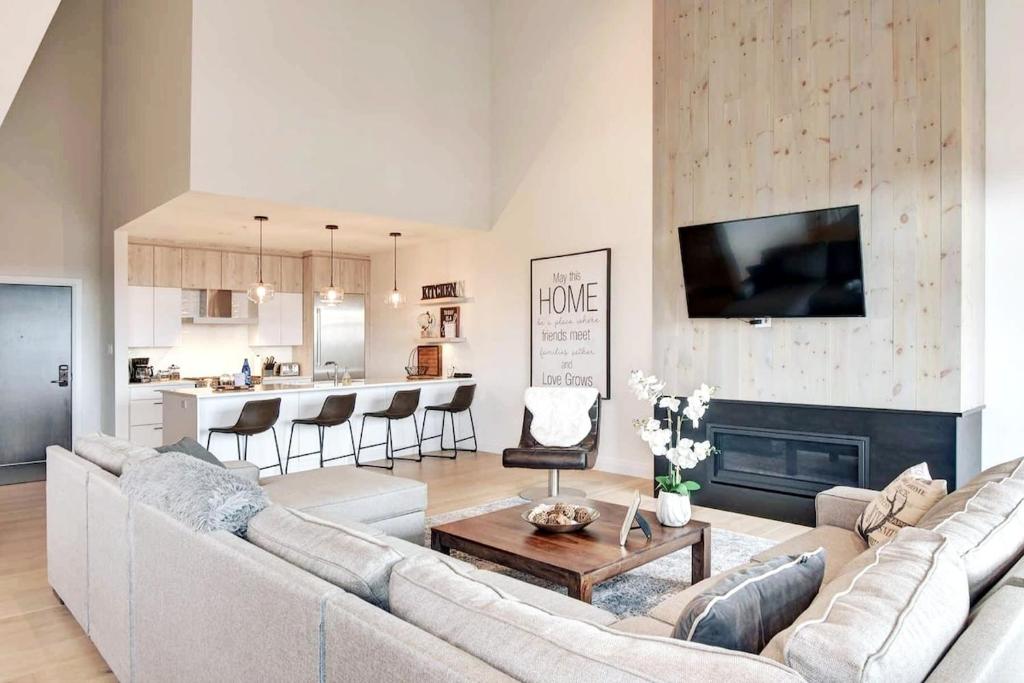 a living room with a large couch and a kitchen at Unique stunning ski in-out condo in Tremblant in Mont-Tremblant